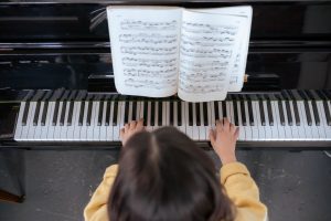 An overhead view of a young woman practicing piano with sheet music.